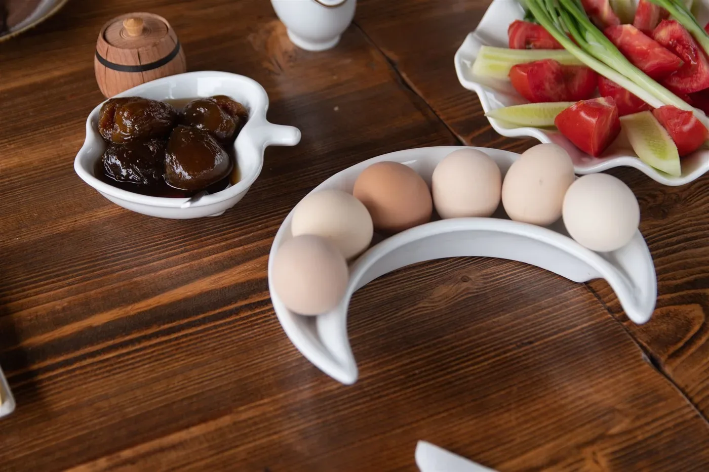Bàn ăn sáng gỗ có trứng, rau củ và mứt trái cây